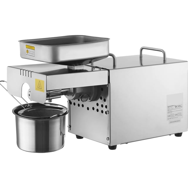 prensa de aceite electrica vevor, máquina extractora de aceite de acero inoxidable de 700 w, temperatura constante de 140 ℃/284 ℉ — Vista frontal en 3/4 de la prensa de aceite VEVOR en acero SUS304 con tolva rectangular superior, cuerpo con asas, orificios de ventilación y tubo de salida lateral que guía el aceite hacia un recipiente colector de acero inoxidable; botón negro de precalentamiento/reversión visible; diseñada para prensado en caliente y extracción de maní, a menudo usada como extractor doméstico portátil para cocina o pequeño restaurante.