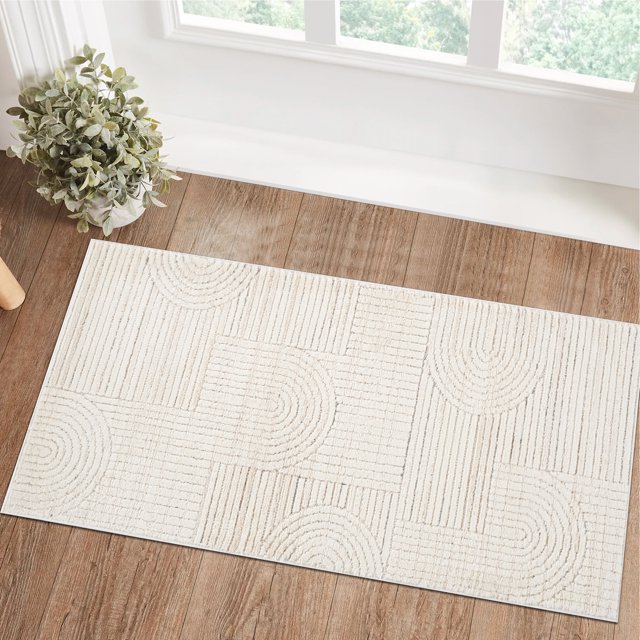 Modern cream beige indoor area rug featuring geometric patterns, placed on a wooden floor by a window with natural light and a potted plant.