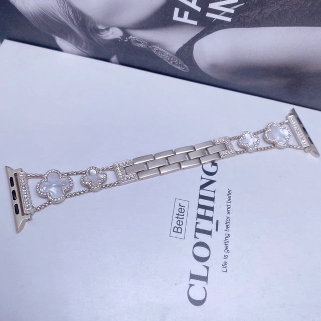 adecuado para apple watch, apple watch se1-8 generación, correa de metal con trébol de diamantes de moda Correa metálica color Starlight con eslabones centrales y tres tréboles decorativos con cristales, adaptadores para interfaz 20/22 mm, vista frontal plana sobre fondo de revista; también suele usarse como pulsera de moda complementaria.