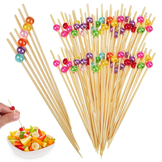 200Pcs Bamboo Appetizer Forks for Food and Drinks, featuring colorful decorative balls on one end. Made of food-grade bamboo, these 4.79-inch disposable skewers are burr-free and easy to grip, ensuring food stays secure. Ideal for appetizers, party snacks, and drink garnishes. Includes a vibrant assortment of skewers displayed in a bundle, with one being used to pick up fruit from a bowl.