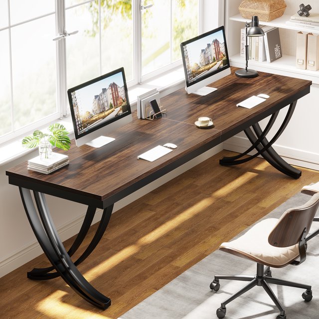 Fnova 78.74" Modern Desk, a wooden computer desk with a wood-like tabletop and curved metal legs in an industrial-modern style. Features include a spacious surface, storage shelf, back baffles, and adjustable foot pads for stability. Ideal for living rooms, kitchens, or home offices, shown in a bright room setup with computers and decor items.