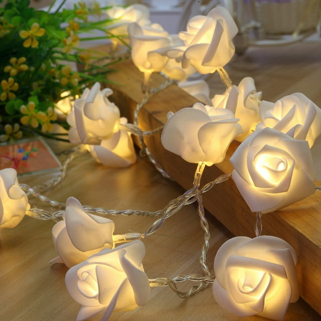 EGNMCR Light Strip, Christmas Lights String Lights Battery Operated Indoor with LED Light White Roses with Warm Light. White rose-shaped LED string lights emitting a warm glow, arranged on a wooden surface. Energy-efficient and decorative, perfect for indoor use, parties, weddings, and festive occasions. Battery-operated with a compact battery box.