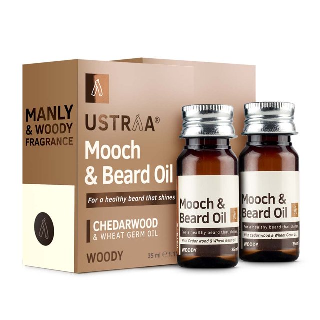 Ustraa Mooch & Beard Oil, 35ml each (Pack of 2), designed for men's grooming and beard care. Features a woody fragrance and is enriched with cedarwood and wheat germ oil to promote beard health, shine, and softness. The amber bottles with silver caps are displayed alongside the branded packaging, emphasizing its SLS and paraben-free formula.