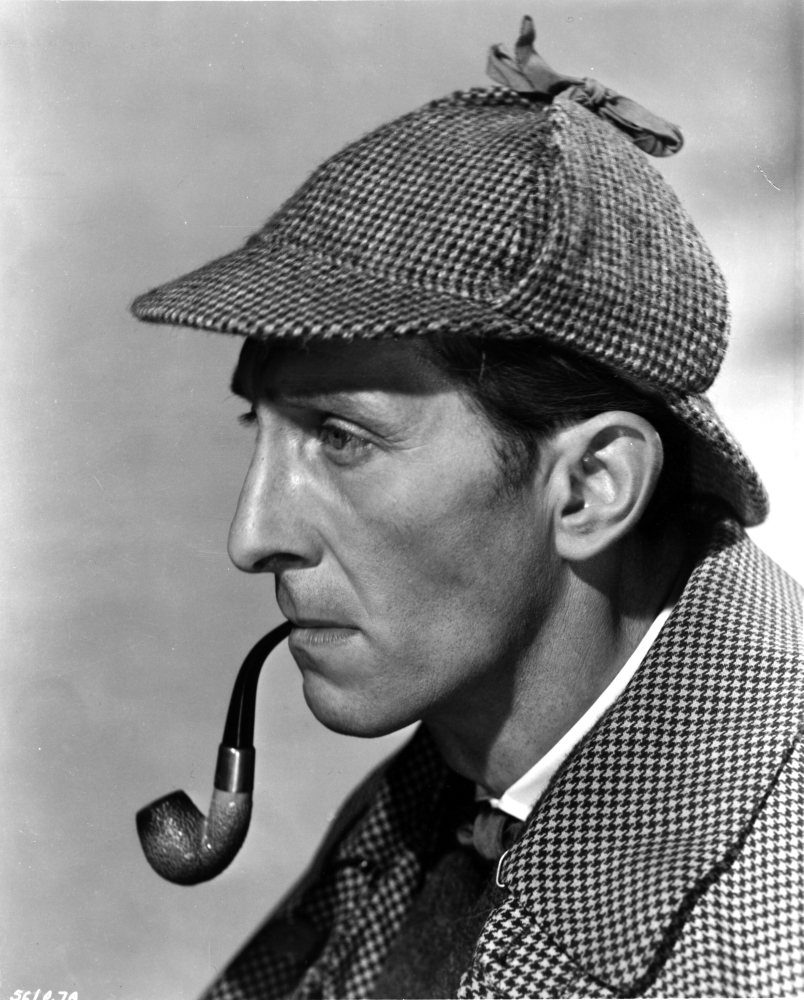 Peter Cushing wearing a detectives costume and smoking a pipe Photo