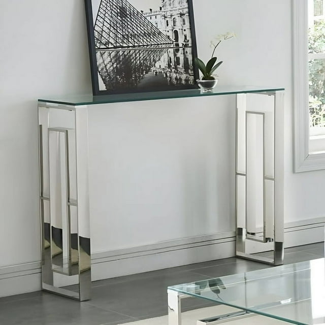 Stainless Steel EVA Console Table with a durable stainless-steel frame and polished silver finish. Features a 10 mm tempered glass top and geometric lattice design. Dimensions are 111.76 cm x 38.1 cm x 76.2 cm (44 in. x 15 in. x 30 in.). Displayed in a modern living room setting with a framed photo and a small potted plant on top.