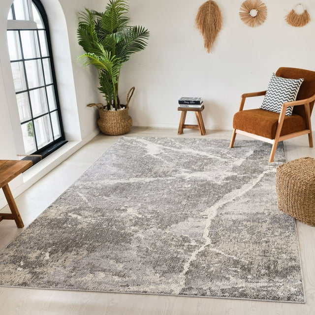 Grey beige marble patterned modern indoor area rug placed in a bright living room with wooden furniture and decorative plants.