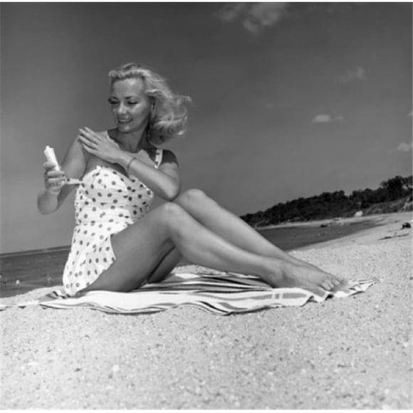 Posterazzi SAL255418010 Young Woman Sitting on Beach & Applying Suntan Lotion Poster Print - 18 x 24 in.