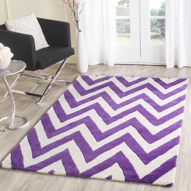 Safavieh Cambridge Kaitlyn area rug featuring bold purple and white zig zag stripes placed on light wood flooring in a modern living space.