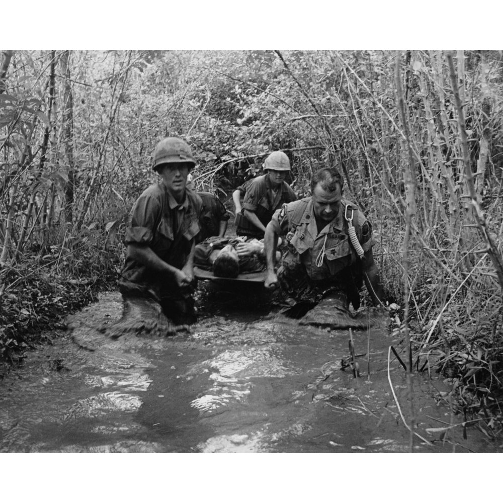Vietnam War. Us Soldiers Carry A Wounded Comrade Through A Swampy Area