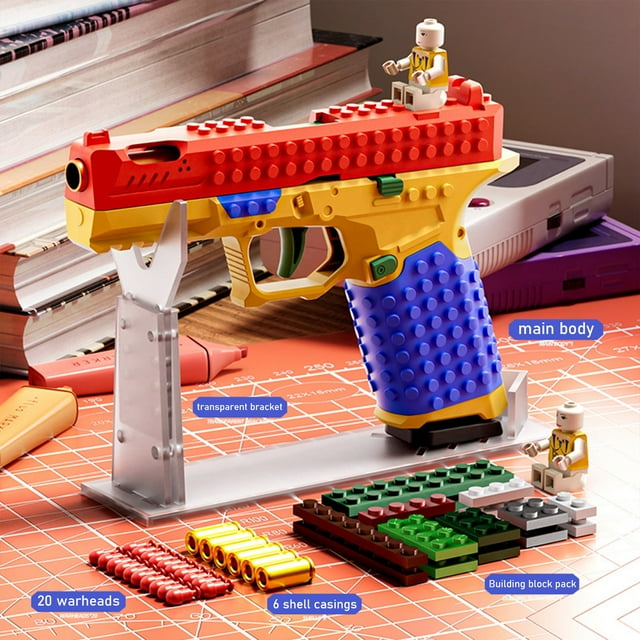 Military DIY Building Block Handle Set Building Block Toy Gun displayed on a transparent stand. This static model features vibrant colors including red, yellow, blue, and green, with a textured block design. Surrounding the gun are additional building block pieces, shell casings, and miniature figurines, emphasizing its creative assembly potential. Display-worthy and ideal for team activities, family bonding, and collection.