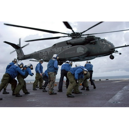 Crew members brace themselves as an MH-53E Sea Dragon lands on the ships flight deck Poster Print by Stocktrek Images