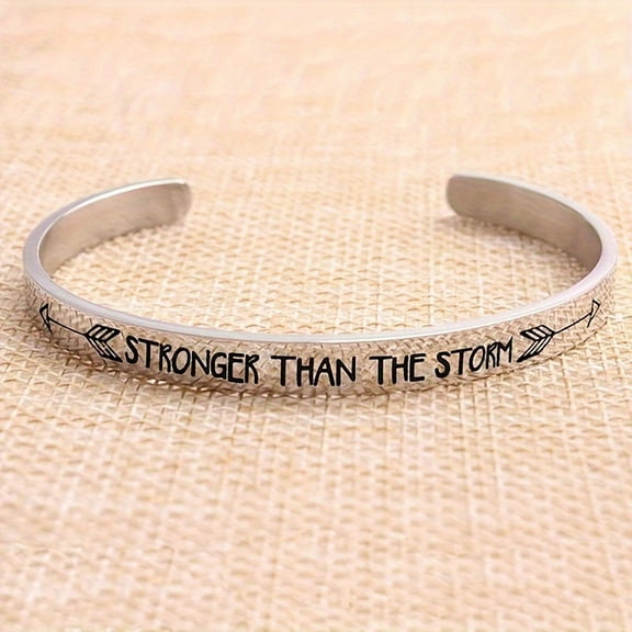 A Personalized Stainless Steel Inspirational Bracelet With An Open Design, Engraved With 'stronger Than The Storm' And Double Arrows On The Outer Side, In The Shape Of A C, Perfect For Christmas