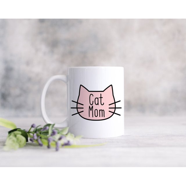 Cat Mom Coffee Mug featuring a minimalist design with a pink cat face outline and the text 'Cat Mom' on a white ceramic mug. Perfect for coffee, hot chocolate, or other beverages. Dishwasher and microwave safe, ideal as a cat-themed gift set for cat lovers.