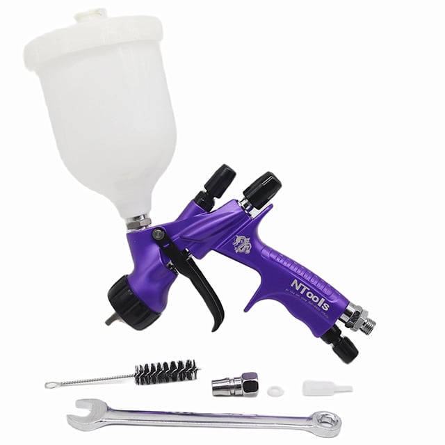 pistola de pintura por gravedad 600ml, bajo consumo y poco overspray boquilla 1.3mm ideal para autos y reparaciones, alta eficiencia. Vista 3/4 de una pistola morada con depósito plástico blanco de 600 ml, gatillo y perillas negras, boquilla y acople neumáticos metálicos, y accesorios visibles (llave y cepillo de limpieza); adecuada para retoques automotrices y trabajos de acabados detallados.
