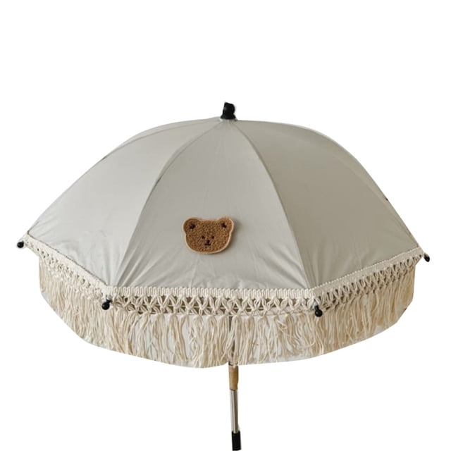 sombrilla con diseño encantador, sombrilla de playa para niños, sombrilla con borlas, sombrilla de playa para niños, artesanía superior Sombrilla de playa NikouMX en tela no tejida color crema, vista frontal centrada; dosel redondo con aplique de osito tejido y franja de borlas trenzadas en el borde, varilla metálica con tramo inferior de madera visible, para sombra en la playa y uso infantil; también adecuada como accesorio decorativo para sesiones de fotos infantiles.