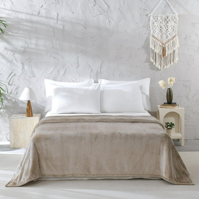 Soft beige Mainstays Plush Blanket covering a bed with white pillows in a bright, textured wall bedroom.