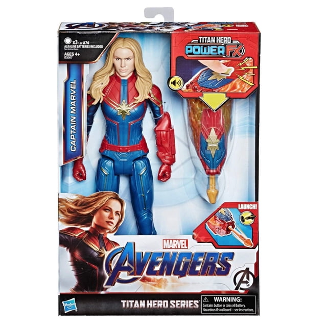 figura de acción marvel avengers endgame titan hero captain marvel figura de 12 pulgadas en empaque frontal, vista centrada; figura con traje azul y rojo, estrella dorada en el pecho, cinturón y guantes rojos y cabello rubio largo moldeado; incluye lanzador Titan Hero Power FX rojo con proyector de disparo a la derecha; caja con logos Marvel y Avengers y texto promocional. Suele usarse como pieza de exhibición en colecciones de figuras de acción.