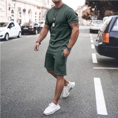 verano manga corta pantalones cortos traje deportivo casual traje ropa de hombre Verde oscuro XL, vista frontal centrada de conjunto de dos piezas: camiseta de manga corta y shorts a juego en tejido fino y liso, cuello redondo y cintura con cordón; modelo caminando en calle urbana con tenis blancos, cómodo para ropa deportiva y uso casual, a menudo usado también para salidas informales o entrenamientos ligeros.