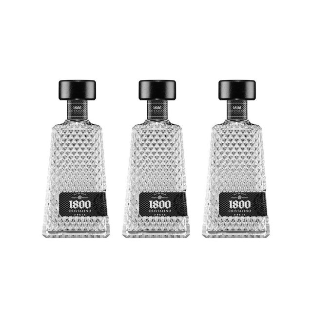 paquete 3 tequila 1800 añejo cristalino 700 ml paquete de tres botellas 700 ml cada una, vista frontal centrada; botellas transparentes con patrón facetado de vidrio, etiqueta negra con logo 1800 y tapa negra cilíndrica sobre fondo blanco; a menudo se usa para regalos o exhibición en barra.