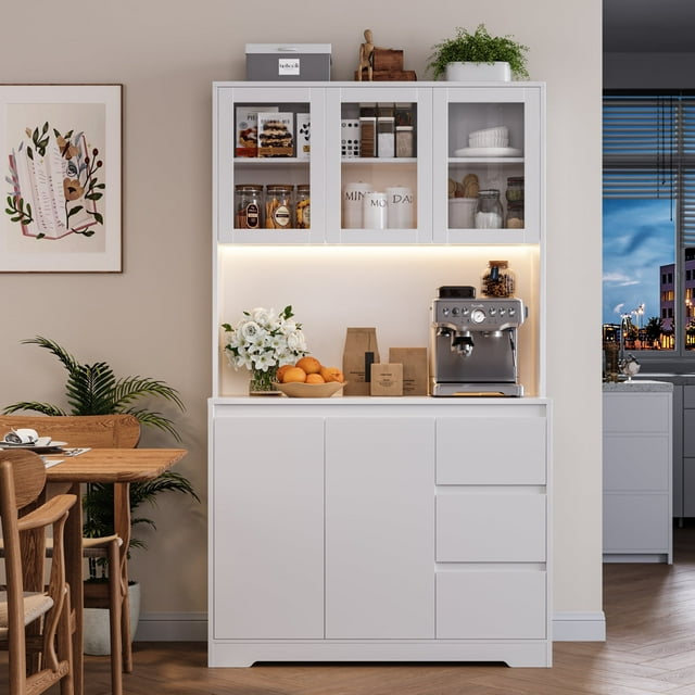 Homfa 70.9'' Kitchen Pantry Cabinet with Charging Station and LED Light in white, featuring three drawers, five doors, and adjustable shelves. The cabinet includes a spacious countertop with a coffee machine and decor items displayed. The upper section has glass doors showcasing organized kitchen essentials, illuminated by warm yellow LED lighting. Positioned in a modern dining area with wooden furniture and a potted plant.