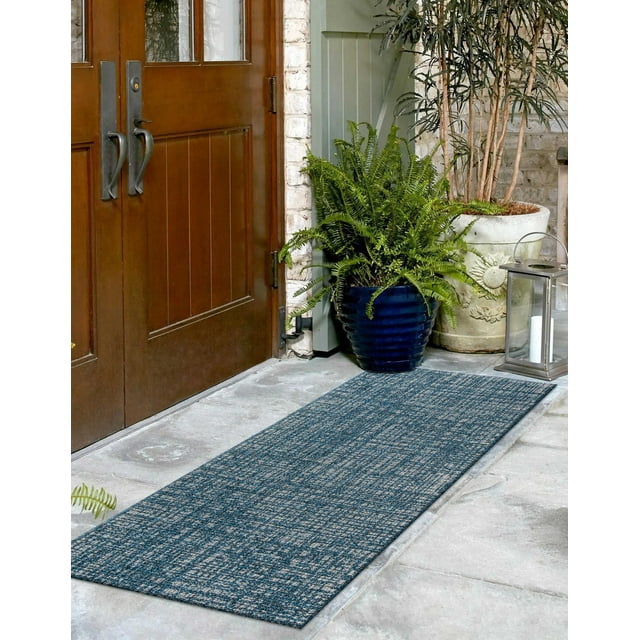 ECARPET Nayah contemporary runner rug in blue and gray tones on stone flooring at an entrance with wooden double doors, surrounded by green potted plants and decorative lantern.