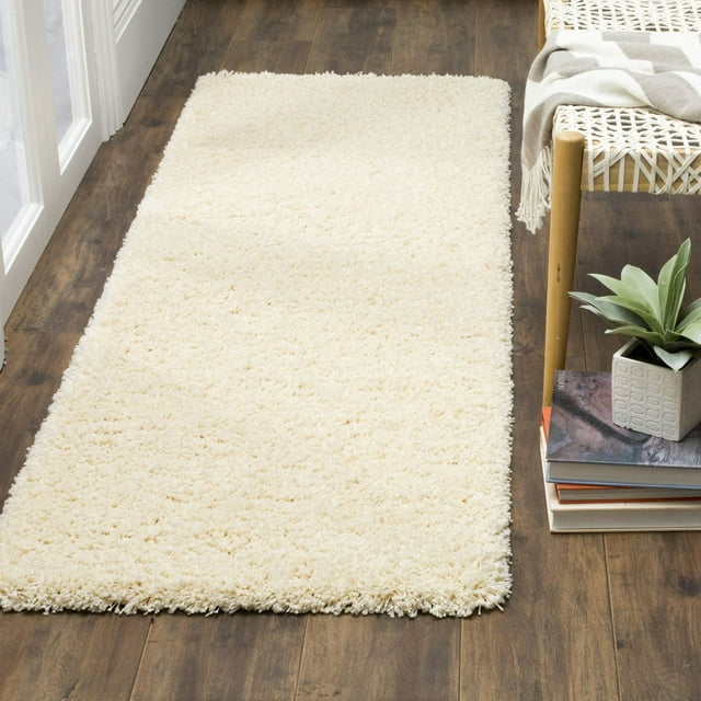 Plush cream shag area rug on wood floor beside woven bench with books and potted plant.