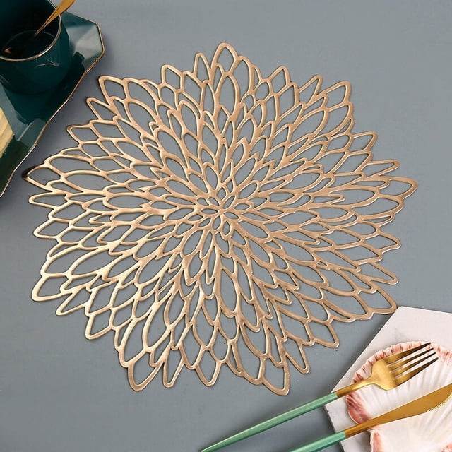 12 pares de manteles individuales dorados surtidos, mantel individual redondo metálico dorado de 38 cm con diseño hueco de hojas decorativas en vinilo laminado, vista cenital centrada sobre mesa que muestra acabado metálico; apto para decoración de mesa en bodas y festivales navideños y a menudo usado también como adorno mural o posavasos improvisado.