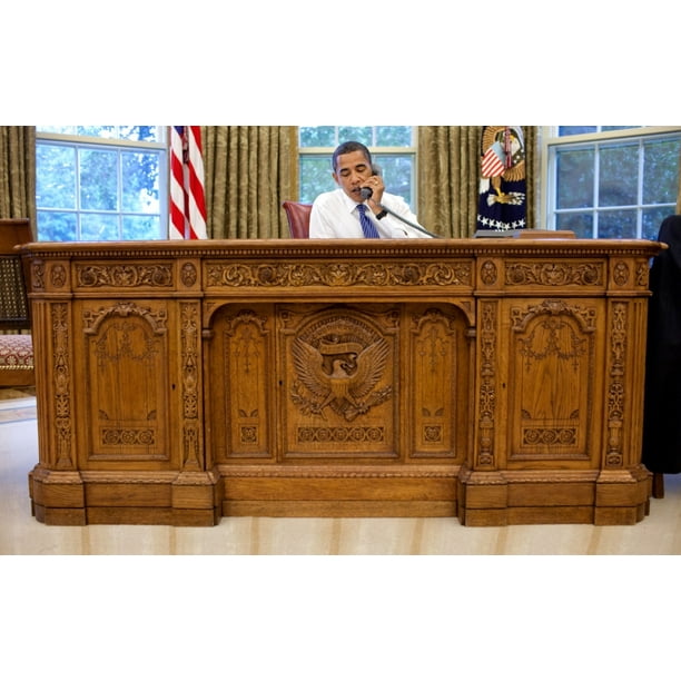 President Barack Obama Sits Behind The Resolute Desk In The Oval Office