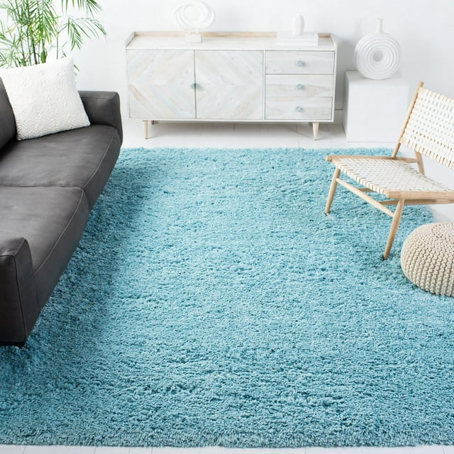 SAFAVIEH Polar Abbot solid light blue extreme plush shag area rug in a bright, modern living room with gray sofa and woven chair.