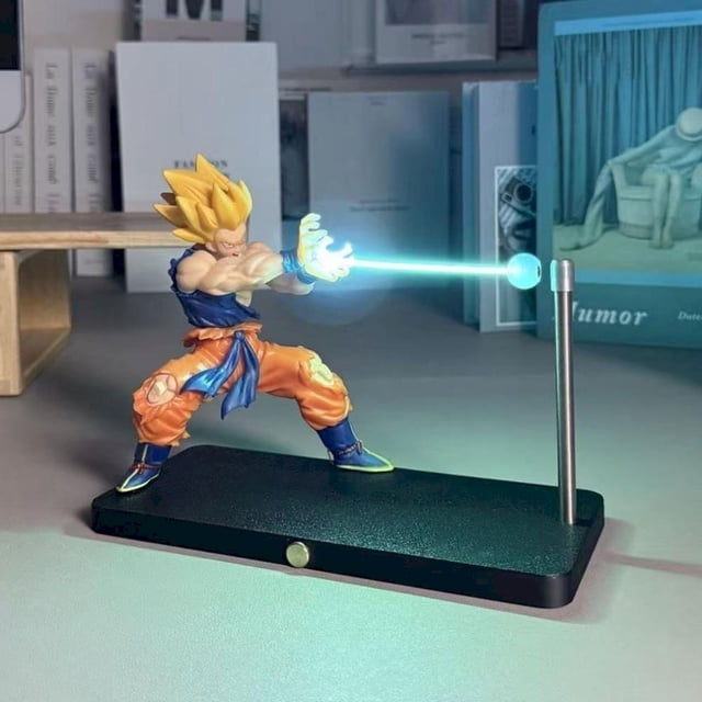 Nikolatoy Super Saiyan Night Light Ornament featuring Kakarotto Son Goku in a Kamehameha wave pose. This Saiyan-themed LED light emits a glowing beam supported by a magnetic stand, perfect for anime enthusiasts. Designed as both a decorative anime peripheral and functional night light, it includes touch-sensitive controls for brightness adjustment and a rechargeable battery with up to 8 hours of use. The sleek black base complements the vibrant figure colors, making it ideal for bedrooms or display shelves.