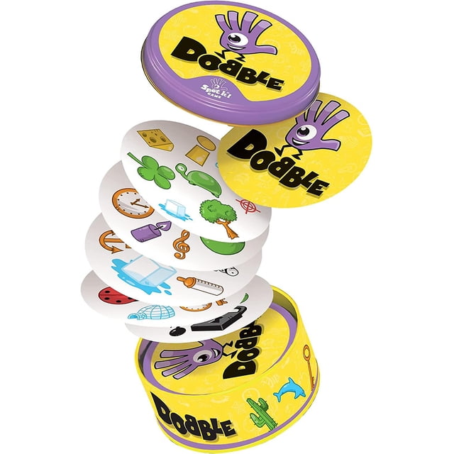 asmodee | dobble | juego de cartas | edades 6 + | 2-8 jugadores | 15 minutos jugando tiempo, surtidos lata redonda amarilla con tapa morada y texto Dobble en primer plano; cartas circulares apiladas y desplegadas con símbolos coloridos (trébol, reloj, árbol, nota musical, cohete) sobre fondo blanco; envase compacto para partidas rápidas, suele usarse para juegos familiares y viajes cortos.