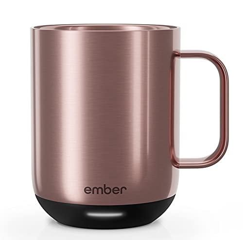 A Rose-Gold Ember Temperature Control Smart Mug 2 App Controlled Heated Coffee Mug on top of a book and a wooden window sill