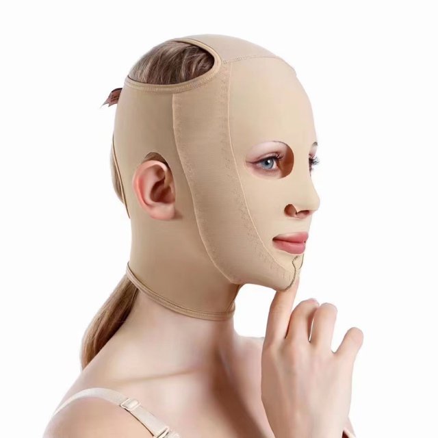 correa para adelgazar la barbilla de la mejilla, máscara facial, vendaje adelgazante, moldeador de masaje facial delgado, reutilizable y transpirable beige: vista 3/4 lateral de modelo con faja facial beige ajustable que cubre frente, mandíbulas y barbilla; tejido elástico transpirable, cierre de hebilla y velcro con tres niveles de ajuste y recorte para orejas; diseñada para sostener y realzar el contorno facial durante sesiones de 40–60 minutos.