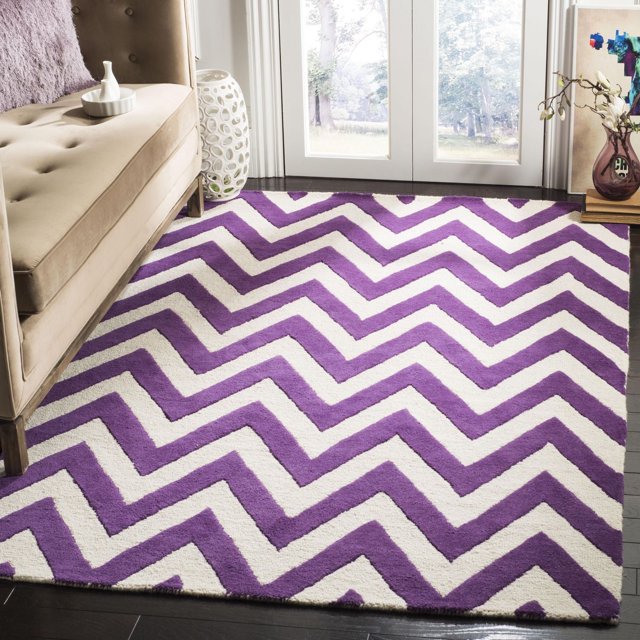 Safavieh Cambridge Kaitlyn area rug featuring purple and white zig zag stripes on dark hardwood floor next to beige sofa.