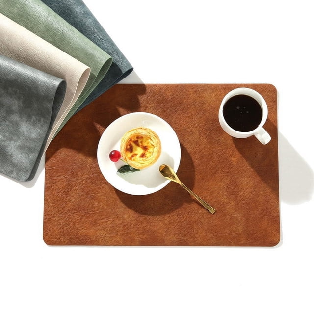 mantel individual con estampado de piel de vaca de cuero pu de primavera, tapete aislante antideslizante cuadrado, mantel de mesa de estilo minimalista, mantel individual de hotel — vista cenital de mantel cuadrado color café en cuero PU con textura tipo piel de vaca, bordes redondeados y superficie antideslizante; colocado con un plato con postre y una taza de café sobre fondo blanco minimalista. A menudo usado como protector de mesa para cenas en hoteles o reuniones pequeñas.