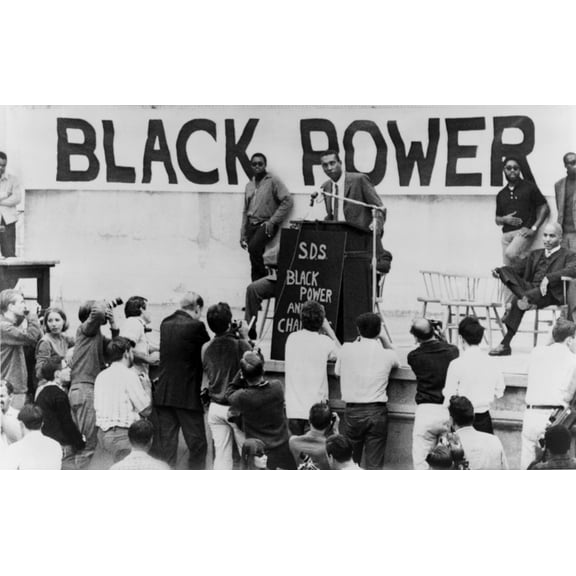 Stokely Carmichael Speaking At The University Of California At Berkeley. A Large 'Black Power' Sign And Sds Initials For The Leftist 'Students For A Democratic Society' Are On The Podium. Ca. 1965-67.