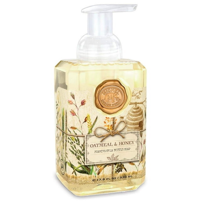 michel design works jabón de manos espumoso avena y miel botella dispensadora frontal con líquido ámbar claro, etiqueta vintage con ilustraciones de avena y colmena y sello dorado de la marca, boquilla de espuma transparente; también apto para usar como jabón de manos en tocador o lavabo pequeño.