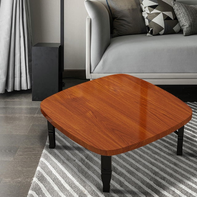 mesa de centro plegable macarena mesa de té cuadrada 80 cm x 35 cm mesita de noche japonesa creativa mesa baja cuadrada color marrón con tablero liso efecto madera de 80 x 80 x 35 cm y esquinas redondeadas; patas plegables negras desplegadas sobre alfombra rayada junto a sofá gris en sala, apta para salón, dormitorio o balcón y a menudo usada como mesa auxiliar para té o escritorio pequeño.