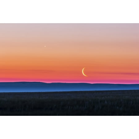 June 24 2014 - The waning crescent moon below Venus rising in the east as seen from over the flat prairie horizon of southern Alberta Canada Mist in the valley creates the blue-grey band below