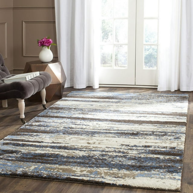 SAFAVIEH Retro Mayson abstract area rug featuring blue, beige, and brown horizontal stripes on hardwood floor near gray tufted chair and white curtains.