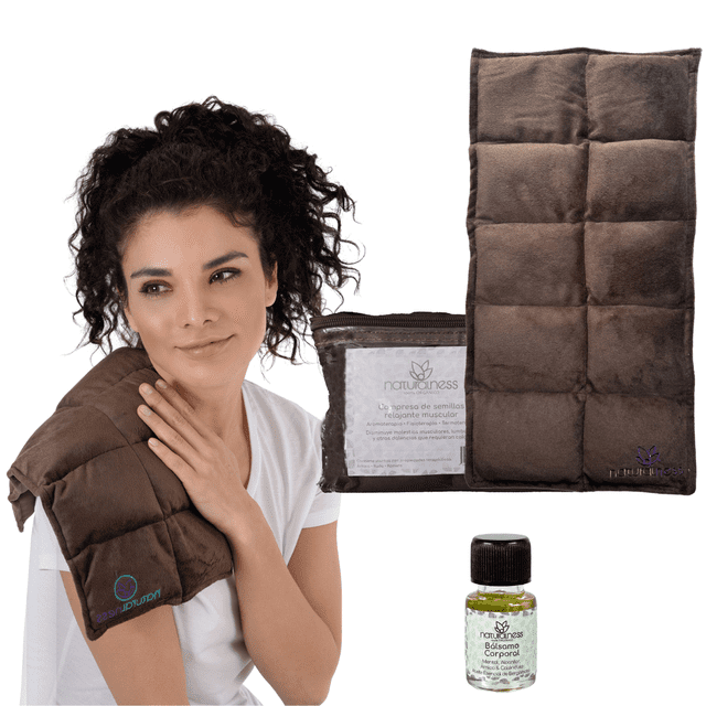 naturalness - compresa muscular grande . Compresa térmica muscular grande en tela marrón con costuras cuadriculadas y relleno de semillas, mostrada frontalmente y colocada sobre el hombro de una mujer; incluye bolsa con etiqueta naturalness y aceite corporal 5 ml para masaje, diseñada para focalizar calor en la zona afectada y amoldarse al cuerpo. A menudo se usa también para aplicar calor localizado en hombros, espalda o piernas.