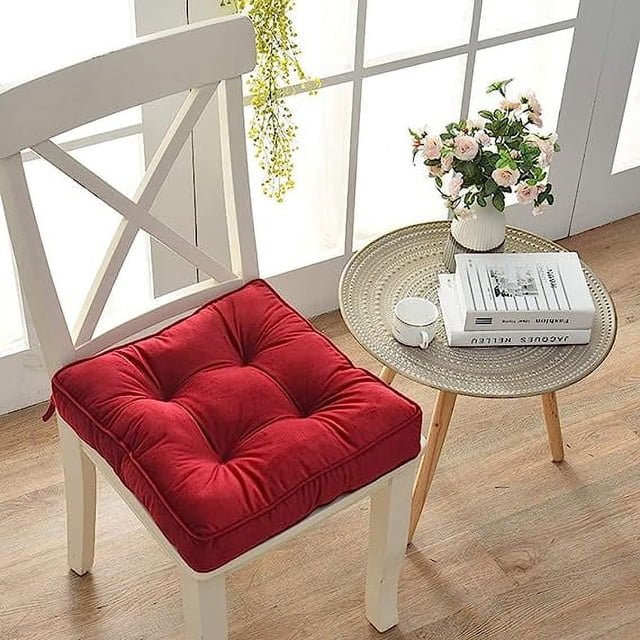 nvzi cojines para silla con asiento cuadrado sólido, antideslizantes, suaves y cómodos, para comedor, cocina, oficina, con lazos (17" x 17" x 3", rojo) cojín cuadrado rojo 17 x 17" sobre silla blanca, vista 3/4; superficie acolchada con capitoné en cuatro botones, tejido poliéster suave, costuras perimetrales, lazos traseros para atar y base antideslizante; en interior junto a mesa auxiliar con taza y flores; también apto como acolchado extra para silla de escritorio o mecedora.