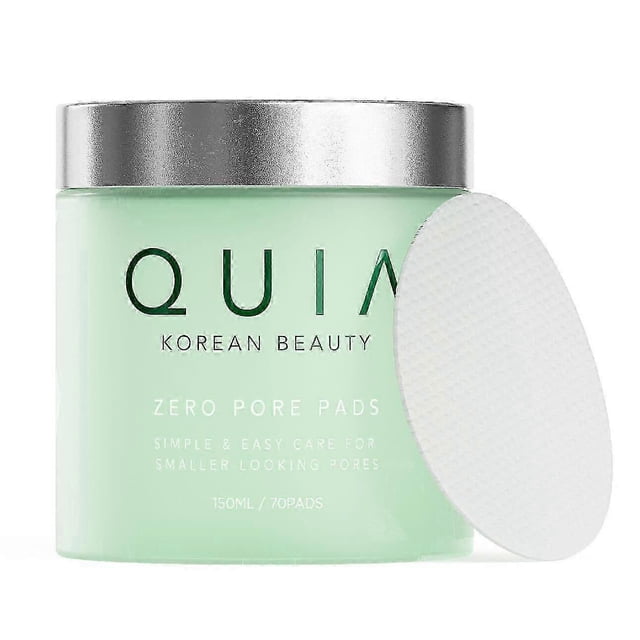 quia zero pore pads, quia double-effect toner, exfoliates and reduces blackheads. Vista frontal de frasco verde menta con tapa plateada y una almohadilla oval texturizada apoyada; 150 ml/70 pads visibles, toallitas portátiles de un solo uso que combinan exfoliación física y limpieza química para eliminar suciedad y exceso de grasa, retirar cutícula y ayudar a reducir la apariencia de poros; aptas para piel grasa y mixta, prácticas para uso diario y viaje.