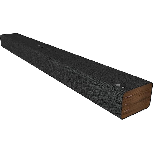 barra de sonido lg 2.1 canales sp2 Barra de sonido LG 2.1 canales color negro con paneles laterales en tono madera, vista 3/4 frontal, cubierta textil negra, logotipo LG visible, controles táctiles superiores y subwoofer integrado de 100 W para sonido envolvente; también usada frecuentemente para música y videojuegos.