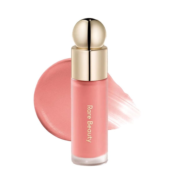 Lightweight Liquid Blush for a Natural Hydrated Look, designed for long-lasting and smudge-proof wear. The product features a sleek cylindrical bottle with a gold rounded cap and a soft pink shade. A swatch of its creamy texture is displayed, emphasizing its blendable formula. Ideal for use as a cheek and lip tint, offering versatile multi-use functionality.