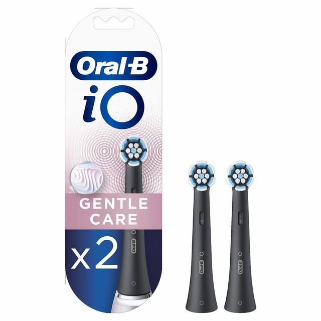 cabezal de cepillo dental oral-b io gentle care negro 2 piezas empaque a la izquierda y dos cabezales negros a la derecha; cabezal redondo con filamentos en patrón circular y anillo azul, cuello de unión estrecho con botón de liberación visible, para reemplazo de cepillo eléctrico en higiene bucal diaria y adecuado como repuesto de viaje.