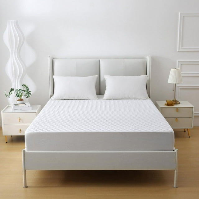 Quilted waterproof mattress protector fitted on a bed with deep pockets, shown in a minimalist bedroom setting.