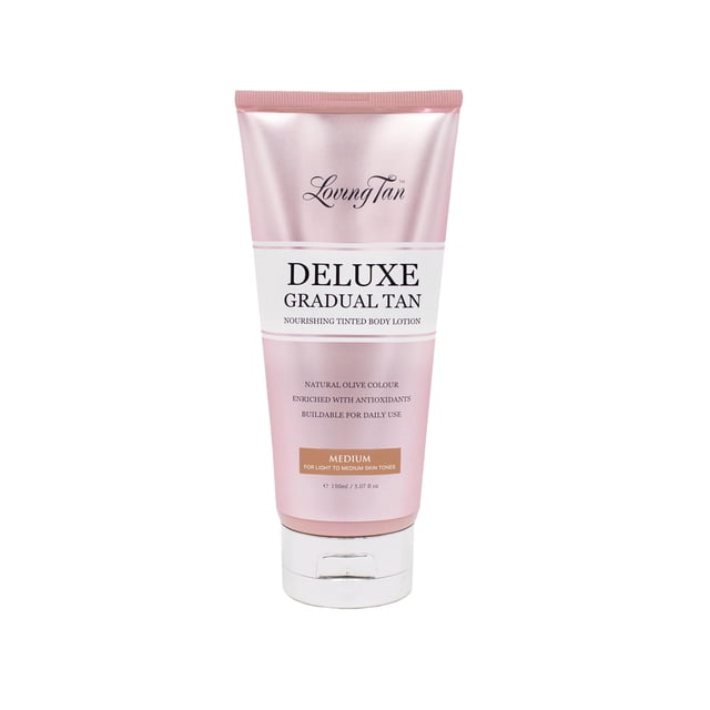 loción bronceadora gradual loving tan deluxe medium 150 ml tubo frontal centrado, envase rosado perlado con etiqueta blanca y texto 'DELUXE GRADUAL TAN', tapa plateada, indica tono Medium y 150 ml; loción autobronceadora gradual adecuada para construir el bronceado con uso diario, a menudo usada como extensor de mousse para prolongar el tono.