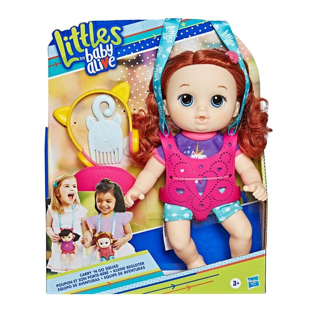 Muñeca Baby Alive Littles Zoe con cabello rojo rizado, camiseta morada con unicornio y short azul con puntos blancos, lleva portabebé rosa con detalles calados. Incluye audífonos amarillos con orejas y peine blanco. Ideal para niñas de 3 años en adelante, fomenta la creatividad y es un juguete de moda perfecto para niñas.