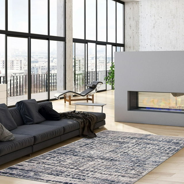 Abstract patterned indoor area rug from Evra Collection placed in modern living room with gray sofa and fireplace.
